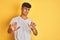 Young indian man wearing white t-shirt standing over isolated yellow background disgusted expression, displeased and fearful doing