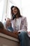 Young Indian mixed-race woman dressed casually sitting on the window sill at home office