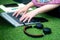 Young Indian woman with a colorful kashmiri shawl typing on a laptop sitting cross legged on grass