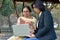 Young Indian woman helping her old retired mother on a laptop sitting in a park in New Delhi, India. Concept - Digital literacy /