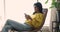 Young Indian woman relax in armchair with smartphone