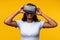 Young Indian woman wearing VR headset on yellow background. Asian female wearing virtual reality goggles.