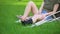 Young injured female with ankle supporting brace and crutches sitting park grass