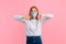 Young insecure woman in a medical protective mask, making a Good-bad sign. Undecided between Yes or no, on a pink background