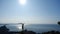 Young inspired traveller raises her hands up standing on the top of a mountain above the sea against beautiful blue sky