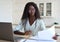 Young intelligent mixed race businesswoman at desk with papers and laptop.