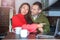 Young interesting couple looking at a laptop at home in the kitchen and holding a smartphone. An international couple on the Inter