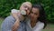 A young international couple in love sitting on the grass, the man holding a flower in his teeth and looking directly