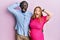 Young interracial couple expecting a baby, touching pregnant belly crazy and scared with hands on head, afraid and surprised of