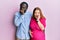 Young interracial couple expecting a baby, touching pregnant belly laughing and embarrassed giggle covering mouth with hands,