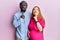 Young interracial couple expecting a baby, touching pregnant belly thinking concentrated about doubt with finger on chin and