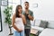 Young interracial couple expecting a baby, touching pregnant belly thinking concentrated about doubt with finger on chin and