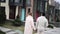 Young interracial couple holds each other hands and walks on street against background of houses