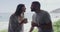 Young and interracial couple kissing and drinking coffee while sitting outside with the beach in the background