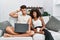 Young interracial couple using laptop at home sitting on the sofa crazy and scared with hands on head, afraid and surprised of