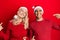 Young interracial couple wearing christmas hat looking confident with smile on face, pointing oneself with fingers proud and happy