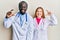 Young interracial couple wearing doctor uniform and stethoscope smiling and confident gesturing with hand doing small size sign