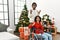 Young interracial couple with woman sitting on wheelchair by christmas tree crazy and mad shouting and yelling with aggressive