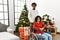 Young interracial couple with woman sitting on wheelchair by christmas tree skeptic and nervous, frowning upset because of problem