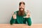 Young irish redhead man wearing casual clothes sitting on the table showing and pointing up with fingers number eight while