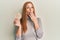 Young irish woman eating healthy rice crackers covering mouth with hand, shocked and afraid for mistake