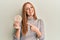 Young irish woman eating healthy rice crackers smiling happy pointing with hand and finger