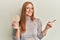 Young irish woman eating healthy rice crackers smiling happy pointing with hand and finger to the side