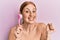 Young irish woman using facial exfoliating brush screaming proud, celebrating victory and success very excited with raised arm