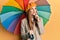 Young irish woman wearing french style holding colorful umbrella serious face thinking about question with hand on chin,