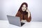 Young Islam woman is smiling face with thinking gesture looking on the blank space in the front of laptop