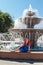 A young Jewess with African pigtails sits on the background of a fountain.