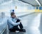 Young jobless business man suffering depression sitting on ground street underground leaning on wall alone looking desperate in