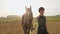 Young jockey girl leads her horse by arena during beautiful sunset, slow motion