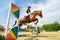 Young Jockey on horse at regional competition  jumping over obstacle