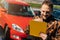 A young joyful man fills out documents about the sale of his car. concept of changing transport