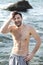 Young joyful man portrait near ocean, topless body