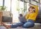 Young joyful mixed race woman wearing headphones and listening to music while using a laptop at home. One cheerful