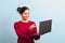 Young joyful woman student with beautiful smile holding an opened laptop and about to press a key on keyboard. investing in