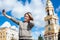 Young joyful woman taking self-portrait photograph with easily handled camera against bell tower of church in Russia