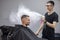 Young Kazakh barber works in a barbershop, a young guy makes a short haircut at a hairdresser, wet his head, water splashes on a