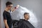 Young Kazakh barber works in a barbershop, a young guy makes a short haircut at a hairdresser, wet his head, water splashes on a