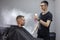 Young Kazakh barber works in a barbershop, a young guy makes a short haircut at a hairdresser, wet his head, water splashes on a