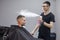 Young Kazakh barber works in a barbershop, a young guy makes a short haircut at a hairdresser, wet his head, water splashes on a