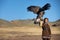 Young kazakh eagle hunter with his golden eagle