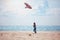 Young kid, boy flying kite at sunny summer day near the seaside