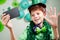 Young kid in green attire celebrating saint patricks day by making video call on mobile phone on decorated background during