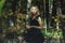 A young kind witch in a black dress with a black mask in a mystical forest in various poses. Art processing