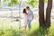 Young kissing couple under big tree with swing