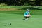 Young Kneeling While Man Playing Golf