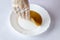 Young kombucha mushroom on a white plate on the table in a man's gloved hand. Tea fermentation.